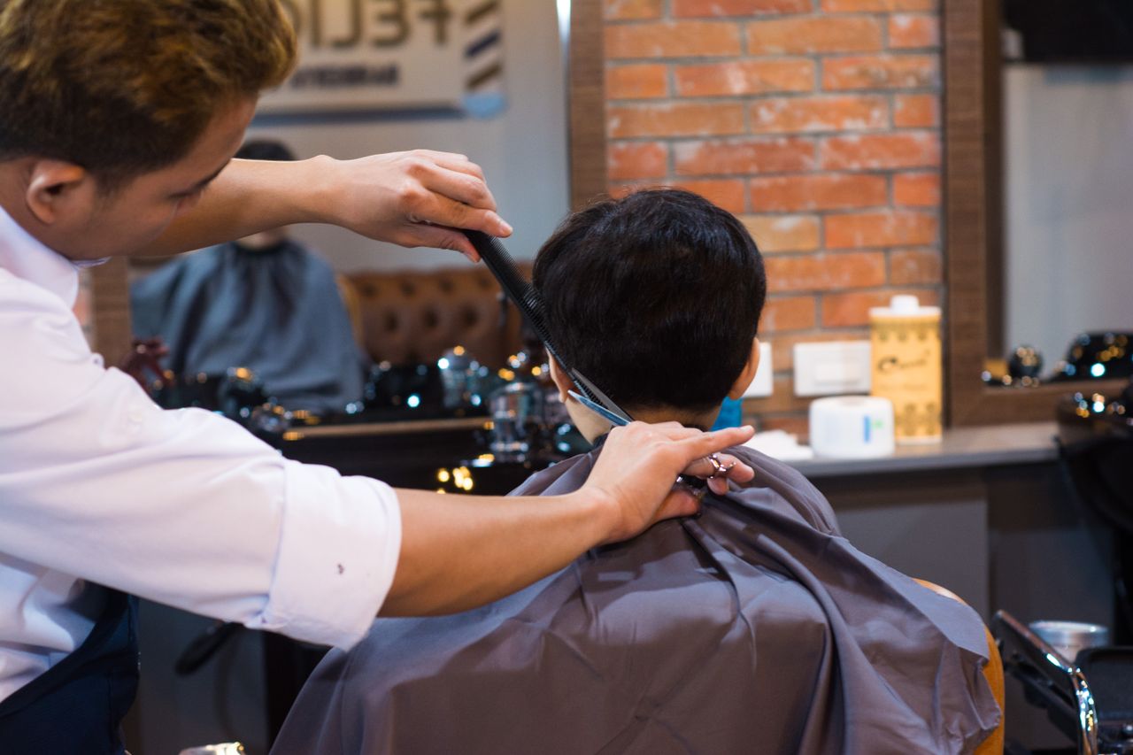 social-feed-img-02 Barber giving a precise haircut to a client in a contemporary barbershop setting.