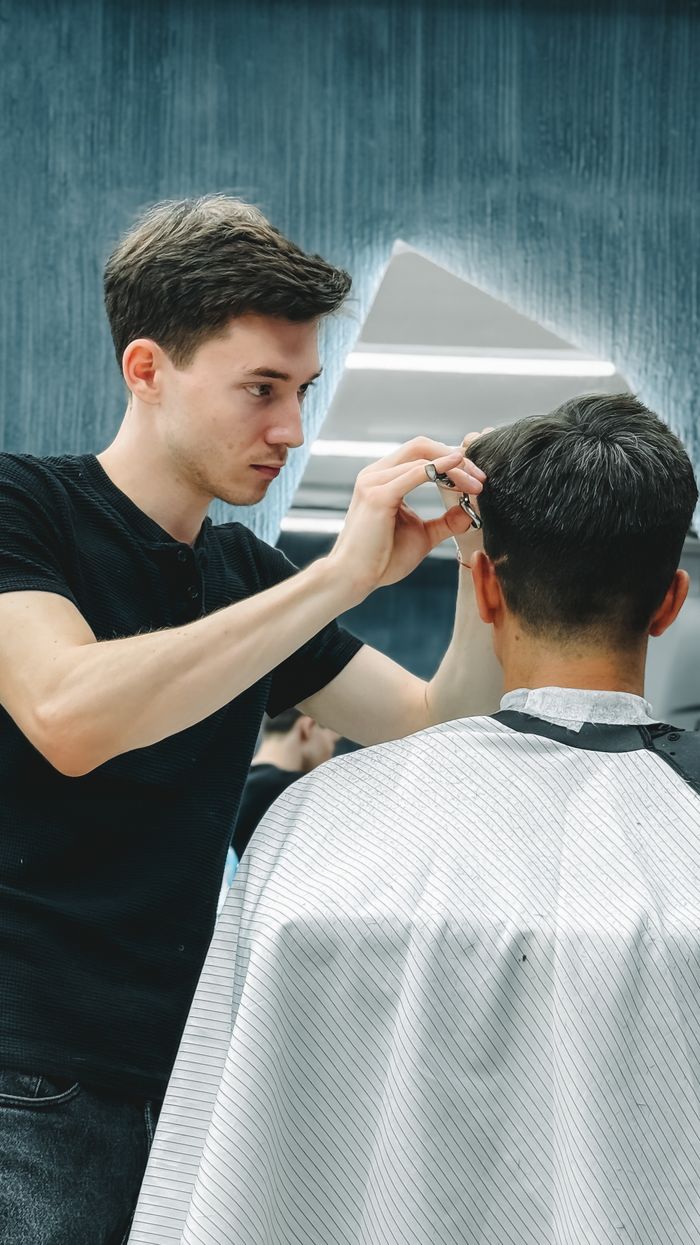 quality-assurance-01 Barber giving a haircut to a client in a contemporary barbershop setting.