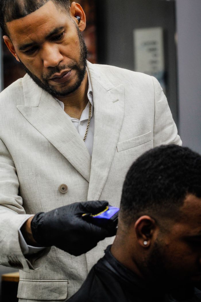 Barber expertly using clippers to trim a client's hair in a modern salon environment.