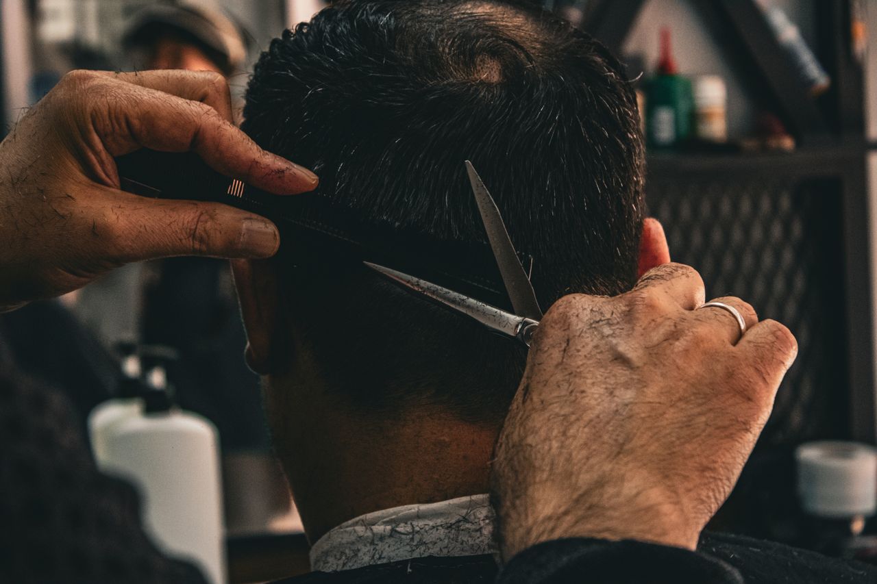 social-feed-img-01 Close-up of a barber expertly cutting a client's hair, highlighting traditional grooming skills.