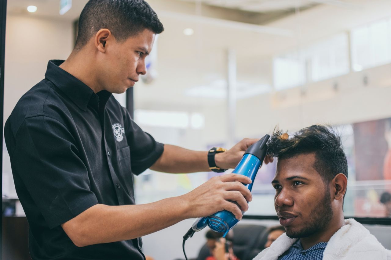 A focused barber styles a client's hair in a modern barbershop setting.