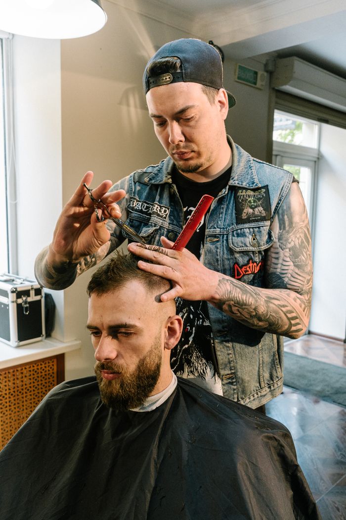 social-feed-img-04 A skilled barber trims a man's hair in a trendy barbershop setting.