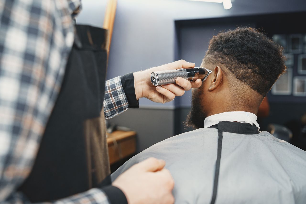 quality-assurance-02 A barber uses clippers to style an African American man's hair in a salon setting.