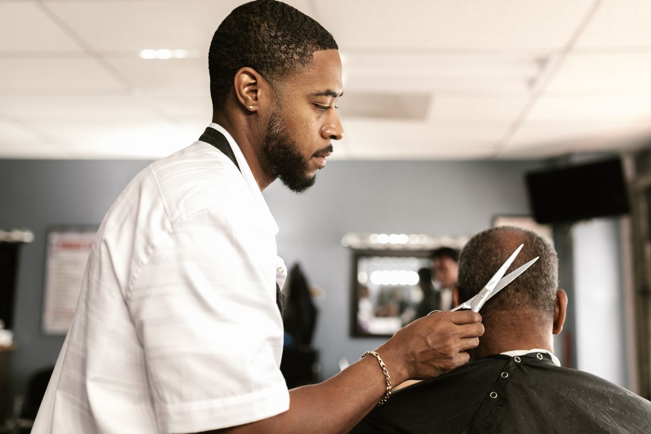 social-feed-img-05 A skilled barber provides a haircut to a client in a modern barbershop setting.